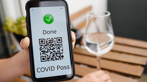 persoon op terras van een café toont covidpas op smartphone